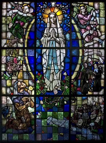 Het glas-in-loodraam met scènes van de stichting van de Lourdesgrot